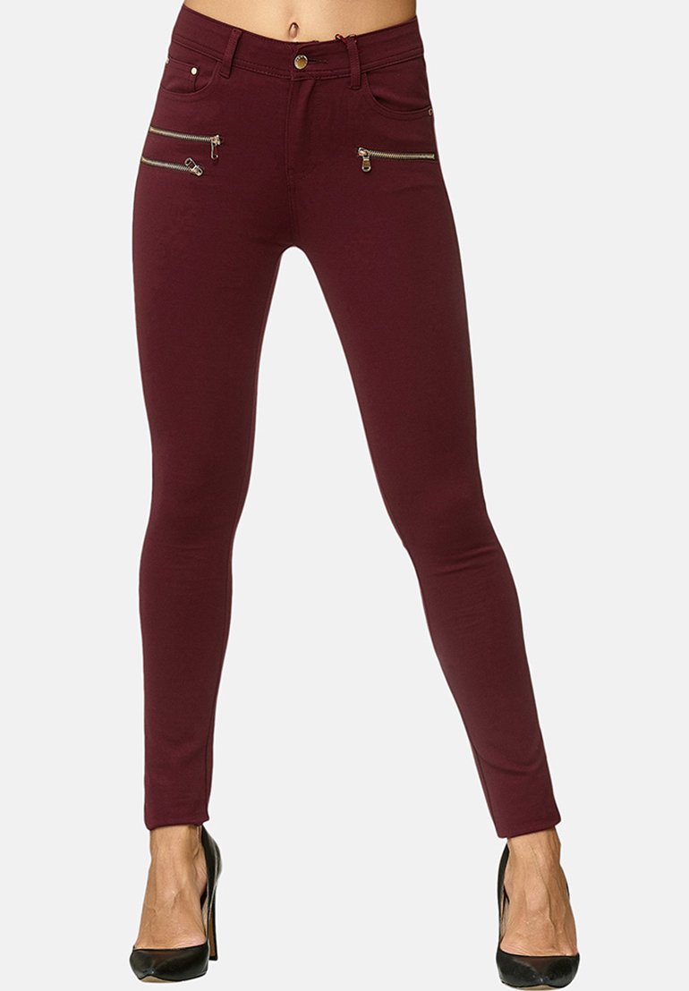 Jeans skinny color bordeaux con due tasche anteriori con zip, dettagli in hardware dorato e un design aderente, realizzati in tessuto elasticizzato per il massimo comfort.