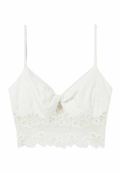Crop top blanc avec des bretelles fines ajustables, présentant un détail de nœud à l'avant et une bordure en dentelle florale à l'ourlet. Tissu doux et lisse.