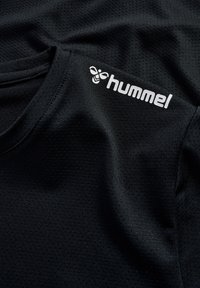 Czarny sportowy t-shirt z teksturowanej tkaniny, z okrągłym dekoltem i białym logo "hummel" po lewej górnej stronie.