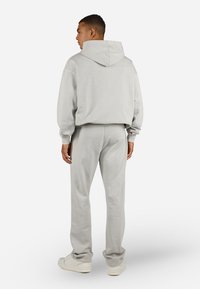 Conjunto de sudadera y pantalones de chándal grises, fabricados en un tejido suave. Sudadera con cordón y bolsillo tipo canguro, los pantalones tienen un corte relajado y puños acanalados.