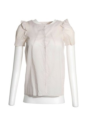 Chemisier rose clair à manches courtes avec volants aux épaules et boutons à l'avant, présenté sur un buste de mannequin blanc.