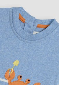 Blå bomulls t-shirt med en krabba broderad i orange och gult, rund hals med en kontrastrikt orange kant, mjuk textur.