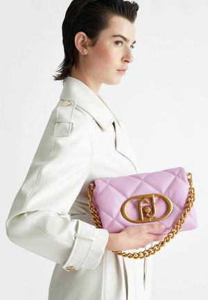 Borsa a tracolla in pelle rosa trapuntata con catena dorata e chiusura a logo. Presenta una forma rettangolare e una texture morbida, appoggiata su un cappotto bianco.