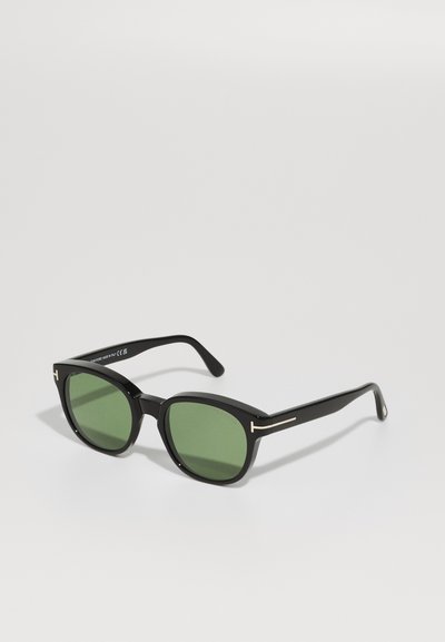 Ochelari de soare negri cu lentile verzi, cu ramă rectangulară, finisaj lucios și detalii aurii pe brațe.