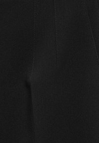 Sección de tela negra con una textura suave, con líneas de costura sutiles y un aspecto ajustado, indicativo de un diseño de prenda estructurada.