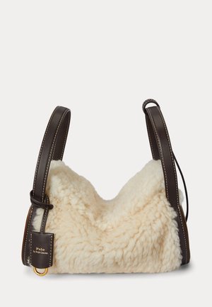 Shearlingtaske i cremefarve med en blød, tekstureret yderside. Brune læderstropper med hvid syning og et guldfarvet metalaksent.