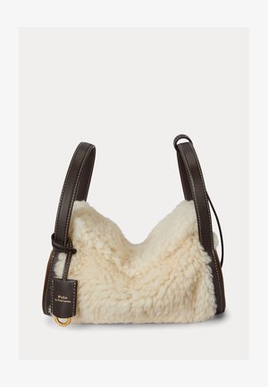 Kermaavärinen lampaannahkalaukku, jossa pehmeä, teksturoidun tuntuinen ulkopinta. Ruskeat nahkahihnat valkoisella ompeleella ja kullanvärinen metalliyksityiskohta.