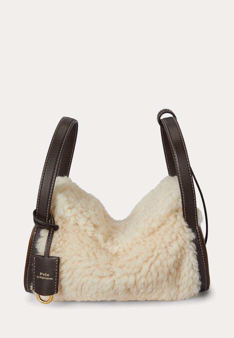 Kermaavärinen lampaannahkalaukku, jossa pehmeä, teksturoidun tuntuinen ulkopinta. Ruskeat nahkahihnat valkoisella ompeleella ja kullanvärinen metalliyksityiskohta.