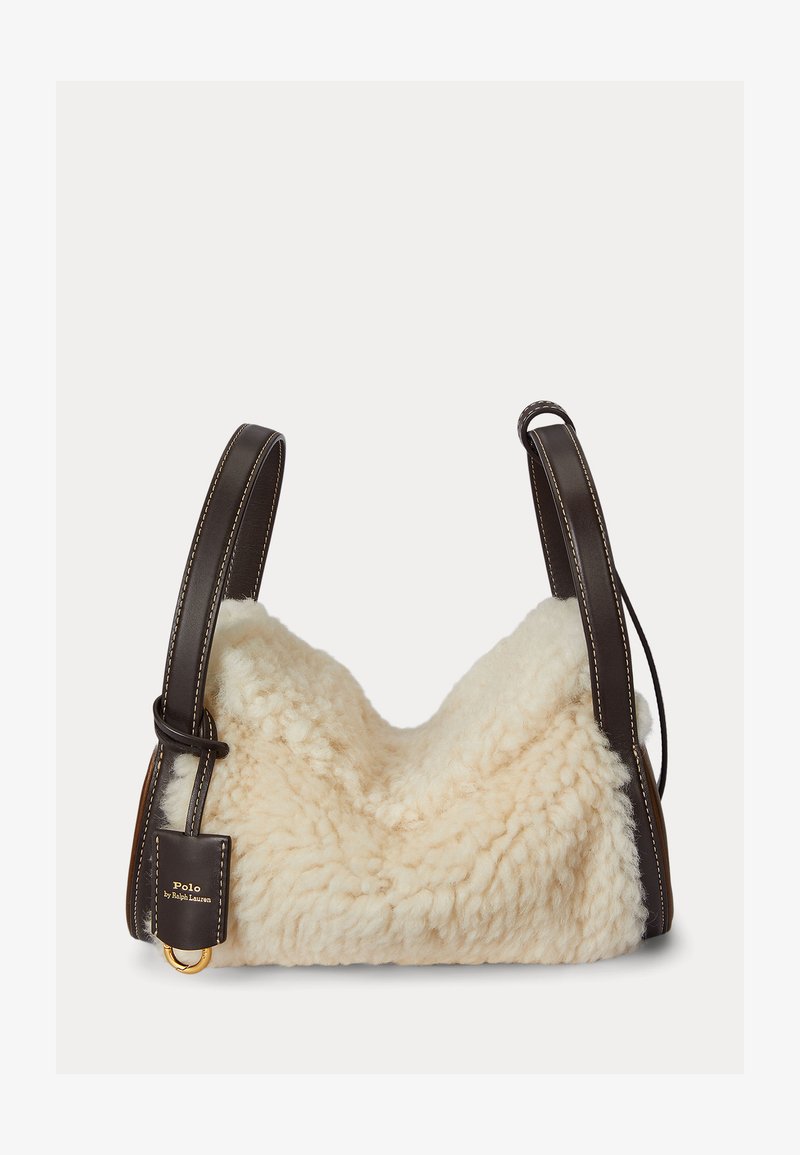 Kermaavärinen lampaannahkalaukku, jossa pehmeä, teksturoidun tuntuinen ulkopinta. Ruskeat nahkahihnat valkoisella ompeleella ja kullanvärinen metalliyksityiskohta.