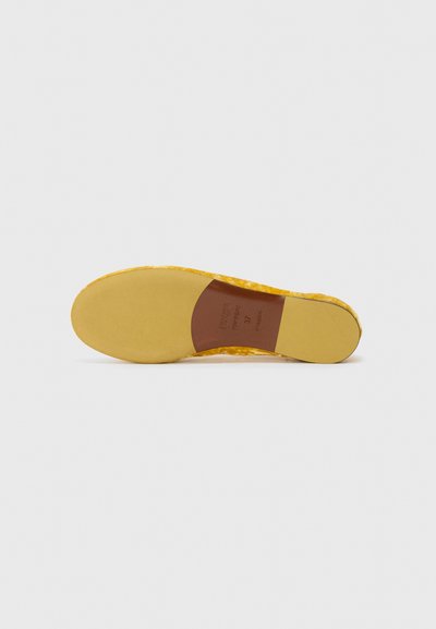 Suela de zapato de goma amarilla con una superficie texturizada. Presenta una plantilla marrón suave marcada con la talla 37. Punta redondeada y tacón ancho.