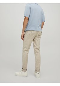 Ljusblå kortärmad polo-tröja, bärs med beige chinos och vita sneakers. Slät tyg och skräddarsydd passform, med en subtil textur.