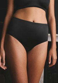 Morbido e elastico intimo nero a vita alta. Presenta bordi senza cuciture e un design a copertura totale.