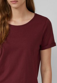 Bordeaux kortemouwen T-shirt van zacht, ademend materiaal; heeft een ronde halslijn en opgerolde mouwen. Gladde textuur en casual pasvorm.