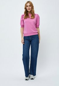 Rosa kortärmad tröja med puffärmar, kombinerad med blå vida jeans och grå sneakers. Enkelt design, bekväm passform.