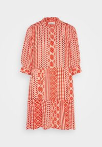 Robe à motifs rouge et crème avec un col haut, des manches bouffantes trois-quarts et une jupe à volants présentant divers motifs géométriques.