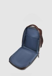 Zaino in pelle marrone con interno blu navy aperto. Dotato di scomparto imbottito e tasca in rete, con manico superiore per un facile trasporto.
