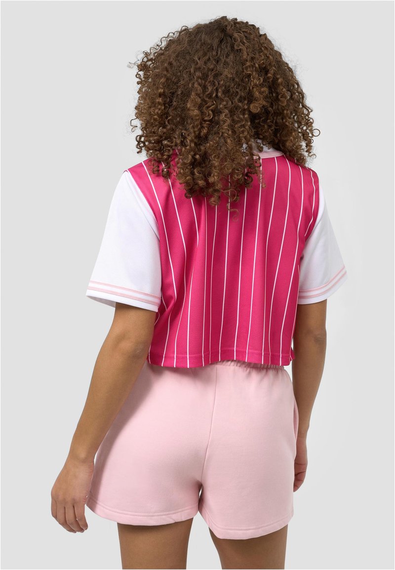 Kratka roza in bela črtasta majica s kratkimi rokavi, kombinirana z roza kratkimi hlačami. Tkanina se zdi mehka z gladko teksturo.