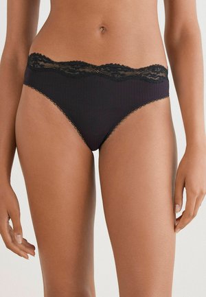 Zwarte geribbelde bikinionderbroek met een scalloped kantafwerking aan de tailleband, met een zachte textuur en een minimalistisch ontwerp.