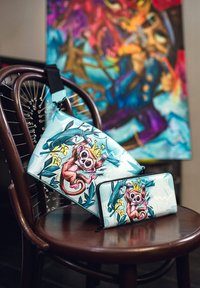 Sada modré a bílé kabelky a peněženky s designem kreslené opice. Vyrobeno z hladkého materiálu se zipovým uzavřením a nastavitelným popruhem.