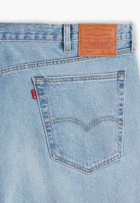 Jeans in denim azzurro chiaro con una tasca posteriore caratterizzata da un design della cucitura curvo distintivo. Etichetta in pelle sulla vita con i dettagli del marchio.