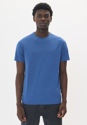 Royal blue cotton t-shirt with a round neckline and short sleeves. Soft texture and simple design, paired with dark denim jeans.