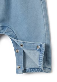 Los tirantes cortos de mezclilla azul claro cuentan con un cierre a presión en el dobladillo y un acabado suave y texturizado con detalles de costura visibles.