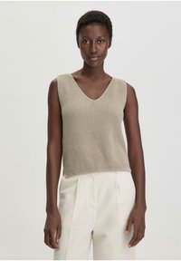 Top senza maniche beige a maglia con scollatura a V; presenta un motivo testurizzato e una vestibilità ampia, abbinato a pantaloni color crema.