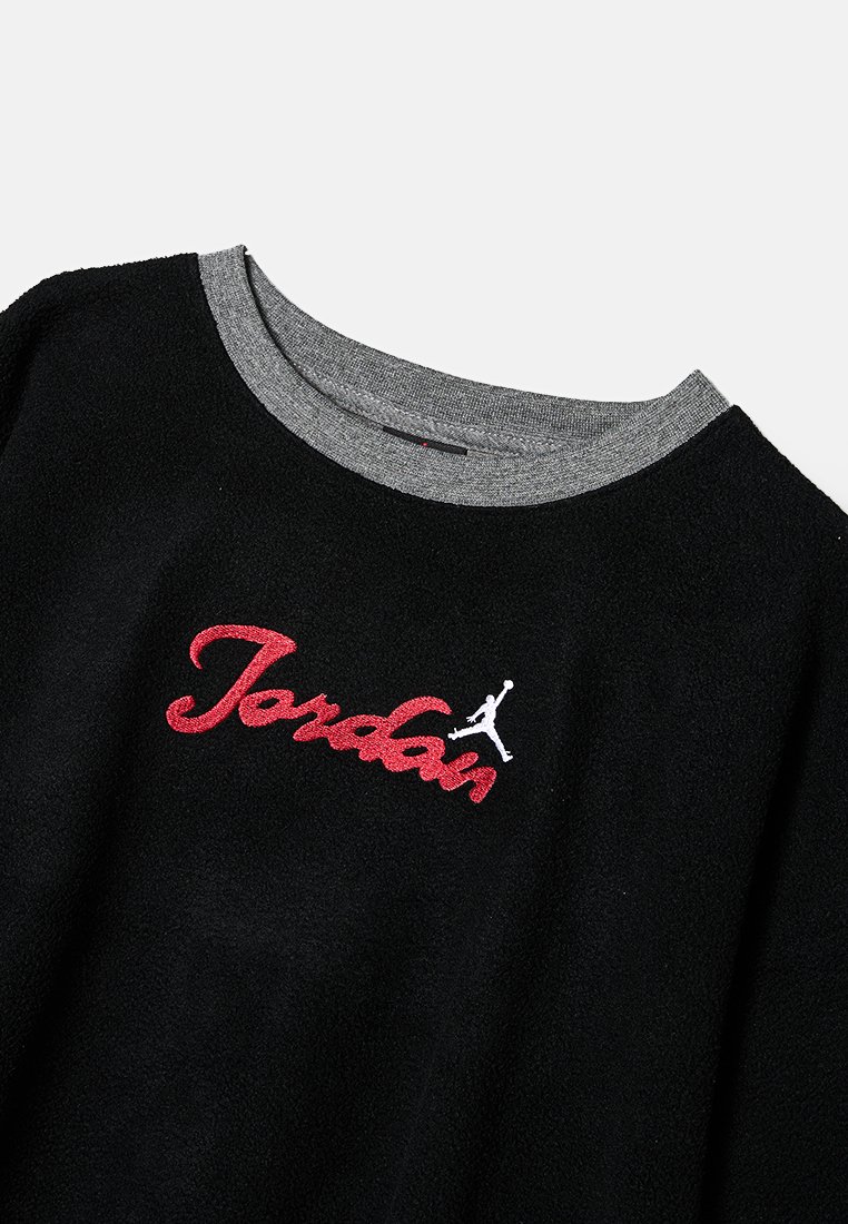 Sweatshirt noir avec un col rond gris, ornée d'un texte "Jordan" brodé en rouge et d'un logo Jumpman blanc sur le côté gauche. Texture douce.