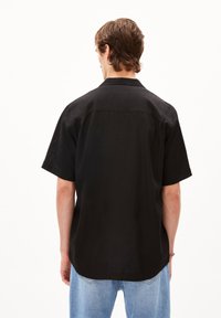 Zwarte kortgebouwde shirt met een klassieke kraag, een gladde textuur en een recht uiteinde. Draag het met lichtblauwe denim jeans.