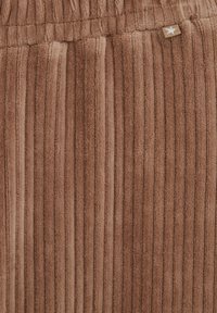 Tessuto a coste marrone con una consistenza morbida, caratterizzato da strisce verticali e una piccola accentuazione di stella metallica.