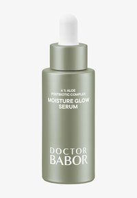 Bottiglia di vetro verde smerigliato con un tappo contagocce bianco. L'etichetta riporta "6% Complesso Postbiotico di Aloe" e "Siero Illuminante Idratante". Il testo è bianco.