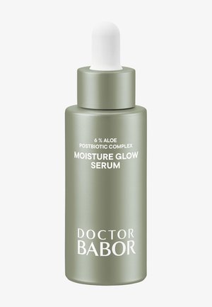 Grön frostad glasflaska med vitt dropplock. Etiketten visar "6 % Aloe Postbiotic Complex" och "Moisture Glow Serum." Texten är vit.