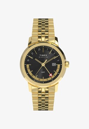Reloj Timex Marlin en tono dorado con un dial negro, marcadores de hora dorados, pantalla de fecha y una correa de brazalete texturizada en dorado.