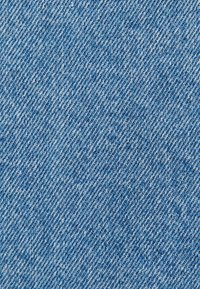 Tissu en denim bleu avec un motif de sergé diagonal montrant des fils blancs et indigo entrelacés.