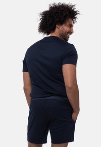 Granatowa, krótki rękaw t-shirt w połączeniu z pasującymi szortami. Materiał wydaje się gładki, z dopasowanym fasonem i minimalnymi szwami.