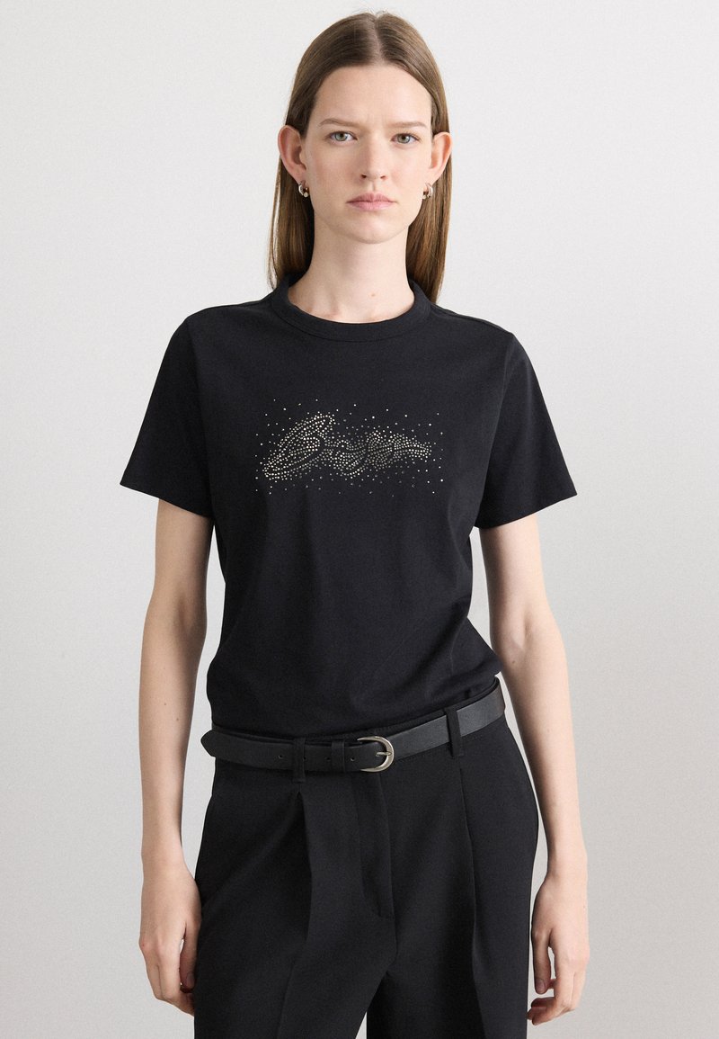 Sort bomulds T-shirt med et skinnende sølv mønster ved brystet. Klassisk rund halsudskæring og korte ærmer. Casual pasform.