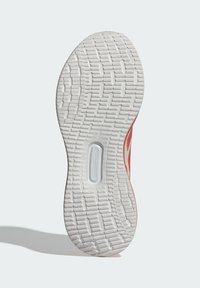 Podeszwa trampka z białą, teksturowaną gumową podeszwą zewnętrzną, posiadająca wzorzysty bieżnik dla lepszej przyczepności oraz widoczną jednostkę amortyzującą w centralnej części.