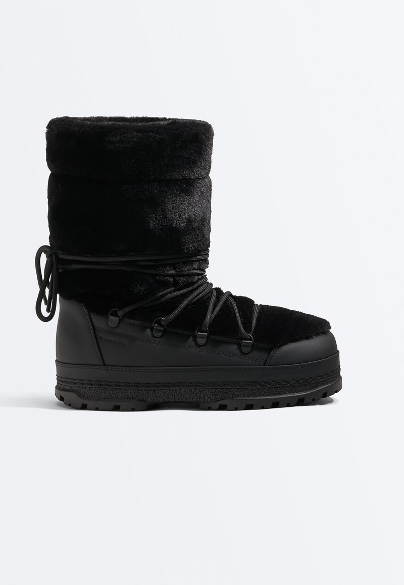 Botte d'hiver noire avec dessus en fourrure épaisse, fermeture à lacets à l'avant, semelle robuste et cheville rembourrée pour l'isolation et une utilisation extérieure.