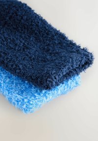 Sada tří měkkých ručníků v různých odstínech modré: tmavě námořnické, středně modré a světle modré, s jemným, texturovaným povrchem.
