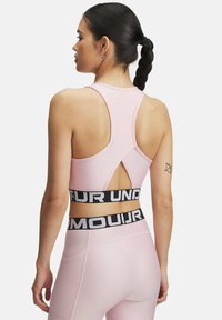 Svetlo roza atletski crop top z dizajnom racerback in izrezljanimi detajli, z črnim blagovnim elastičnim trakom pod prsnim delom.