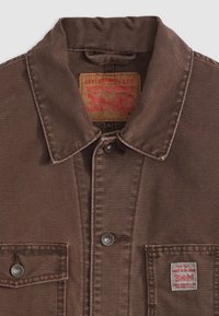 Chaqueta de mezclilla marrón de Levi Strauss & Co. con cuello, cierre de botones en la parte delantera, dos bolsillos en el pecho y parches de la marca visibles en el cuello y el bolsillo.