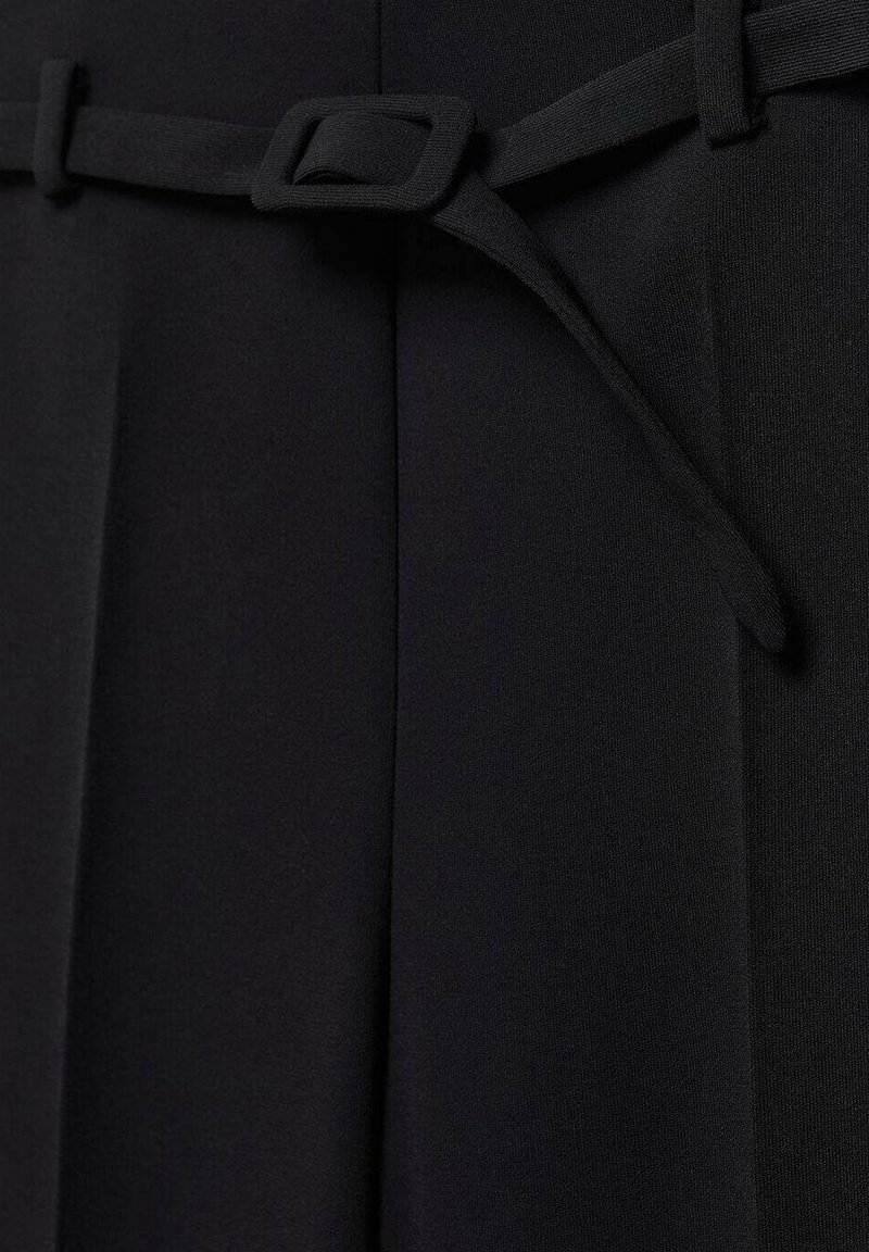 Schwarzes Kleid mit einer glatten Stofftextur, einer taillierten Taille mit einer quadratischen Schnalle und scharfen Falten für zusätzliche Designdetails.