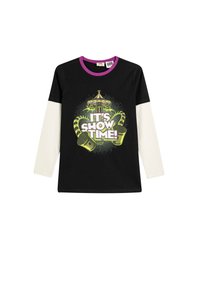 Schwarzes Langarm-T-Shirt mit weißen Ärmeln, das einen grafischen Druck in Grün und Lila zeigt mit dem Aufdruck "Es ist Show-Zeit!" im Zirkusthema-Design.
