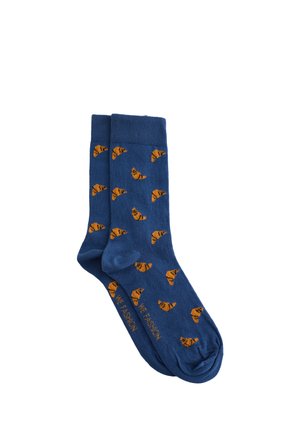 Modré bavlnené ponožky s celoplošným vzorom oranžových croissantov. Žebrované manžety a hladká štruktúra zvyšujú pohodlie a priliehavý strih.