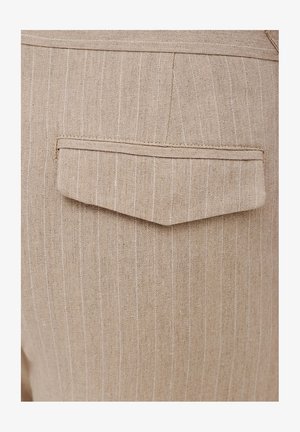 Beżowa tkanina lniana z cienkimi białymi paskami, z kwadratową tylną kieszenią z wyszywaną bordiurą. Brak widocznych elementów metalowych lub ozdób.