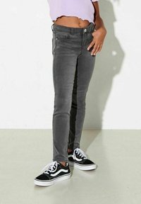 Grå denim skinny jeans med en slät yta, fem fickor och knappstängning, kombinerat med svarta och vita sneakers.