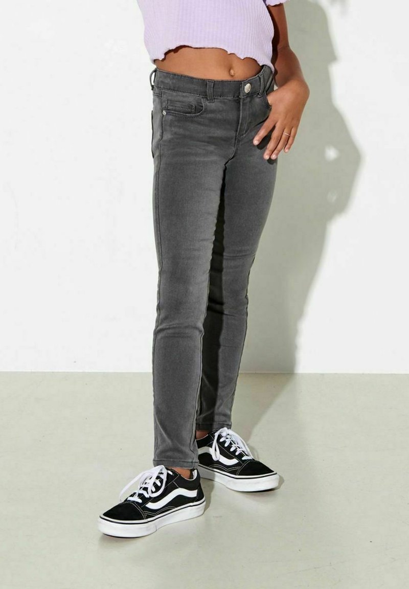 Grå denim skinny jeans med en slät yta, fem fickor och knappstängning, kombinerat med svarta och vita sneakers.