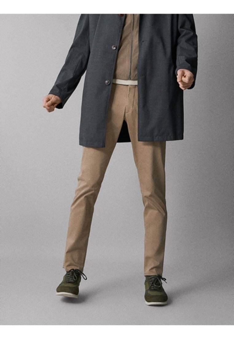 Pantaloni beige, cappotto grigio scuro, camicia chiara, sneakers verdi. Design semplice, vestibilità dritta, texture liscia, accenti hardware minimi.