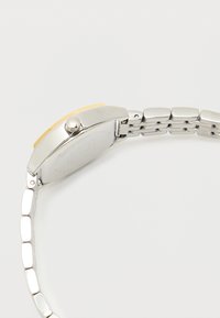 Silver metal watch with a gold-tone rectangular face, textured bezel, and bracelet-style band featuring smooth, rounded links.