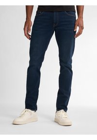 Granatowe dżinsy o slim fit, wykonane z denimu, z przednimi kieszeniami i subtelnie przeszyciami. W połączeniu z białymi sneakersami.